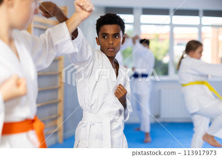 Boy and girl training karate techniques in studio 113917973