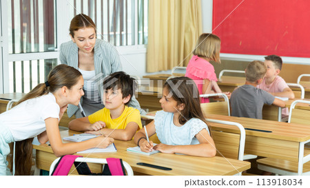 Preteen schoolchilds working in groups at lesson 113918034