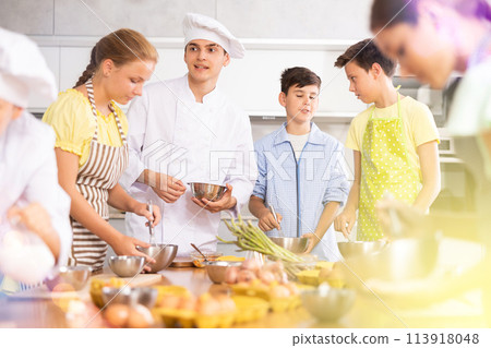 In cooking class, guy cook with bowl in hands tells children participants culinary ticks and tricks In cooking class, guy cook with bowl in hands tells children participants culinary ticks and tricks 113918048