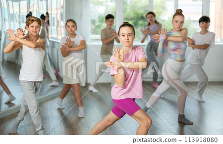 Woman teacher in background dances with students, inspects and observes skill of dancers 113918080