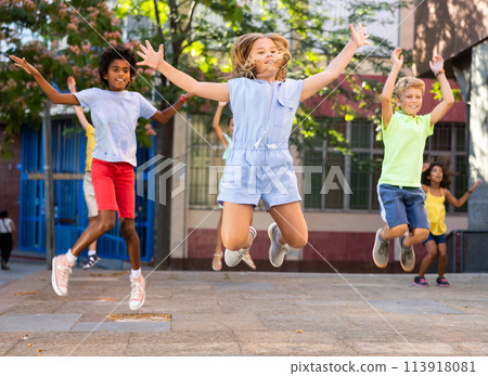 Happy tween girl jumping with friends on city street 113918081