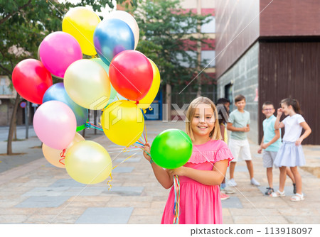 Girl with balloons standing outdoors 113918097