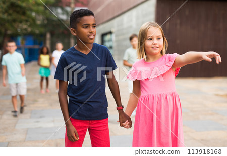 Preteen girl walking with african american friend along city street Preteen girl walking with african american friend along city street 113918168