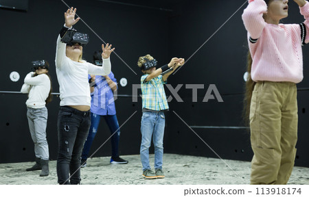 Tweenagers in virtual reality goggles playing video games Tweenagers in virtual reality goggles playing video games 113918174