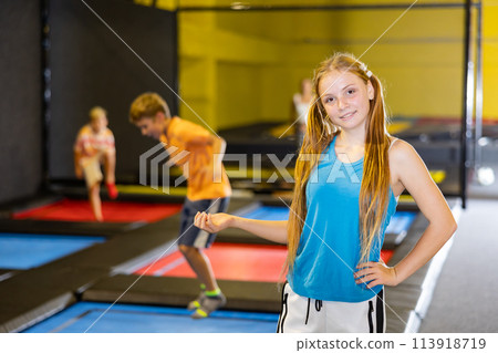 Happy teenage girl standing in indoor trampoline arena 113918719