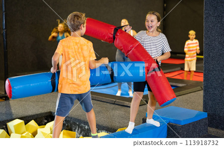 Team of friends playing with inflatable sticks in amusement park 113918732