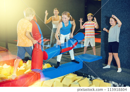 Children having funny wrestling by inflatable logs with his friends in amusement playground Children having funny wrestling by inflatable logs with his friends in amusement playground 113918804