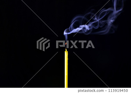 extinguished candle with a smoldering wick exudes smoke on a black background 113919450