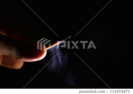 fingers holding an extinct smoking match on a black background fingers holding an extinct smoking match on a black background 113919473