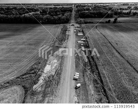 High angle view of a road construction project cutting through an agricultural district of farm fields. High angle view of a road construction project cutting through an agricultural district of farm fields. 113919543
