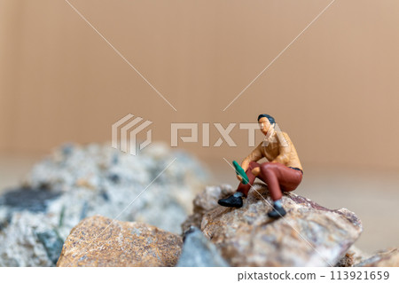 Miniature people , A young man sipping beer while sitting on the rock 113921659