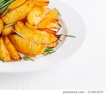 Baked potato wedges with rosemary on plate 113922875