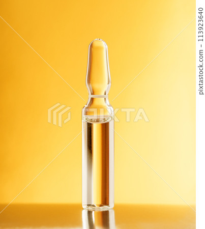 Glass ampoule on a gold orange background. Blister with liquid. Pharmaceutical equipment concept 113923640