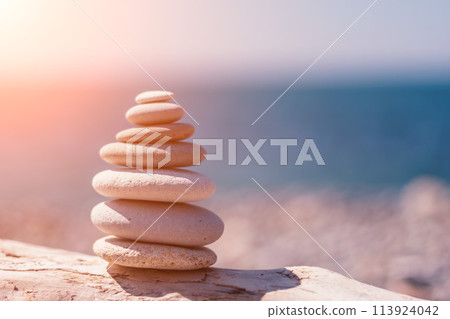 Pyramid stones on the seashore on a sunny day on the blue sea background. Happy holidays. Pebble beach, calm sea, travel destination. Concept of happy vacation on the sea, meditation, spa, calmness. Pyramid stones on the seashore on a sunny day on the blue sea background. Happy holidays. Pebble beach, calm sea, travel destination. Concept of happy vacation on the sea, meditation, spa, calmness. 113924042