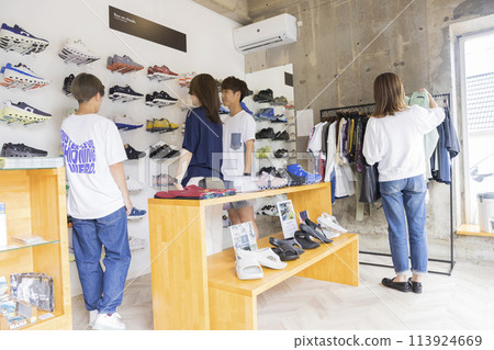 一對年輕夫婦、一名婦女和一名店員在服裝店購物 一對年輕夫婦、一名婦女和一名店員在服裝店購物 113924669