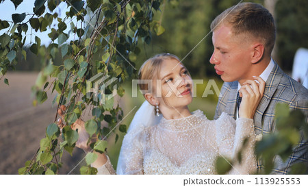 The bride and groom enjoy each other by the branches of a birch 113925553
