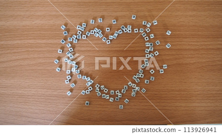 Heart from alphabet white beads blocks with letters in heart random letters around top view wooden background 113926941