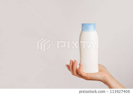 Woman hand holding white bottle of shampoo or hair conditioner on white background, copy space Woman hand holding white bottle of shampoo or hair conditioner on white background, copy space 113927408