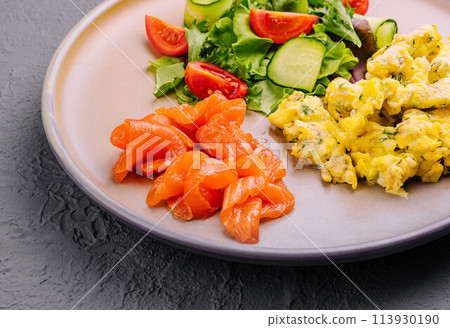 Scrambled eggs with salmon and tomato and cucumber salad Scrambled eggs with salmon and tomato and cucumber salad 113930190