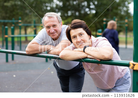 Elderly man and woman posing in open-air sports bars complex Elderly man and woman posing in open-air sports bars complex 113931626