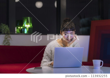 Young woman looking at laptop screen Night image at home 113932255