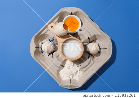 Dark blue background against a set of ingredients for homemade baking, flat lay with eggs, flour, nuts and milk. Top view with copy space for adding text Dark blue background against a set of ingredients for homemade baking, flat lay with eggs, flour, nuts and milk. Top view with copy space for adding text 113932261