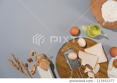 A group of baking ingredients lay flat on pastel blue kitchen table including sandwich, eggs, flour, nuts decorated with a few baking utensil. Copy space for advertising culinary product 113932277