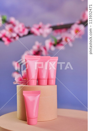 Pink tubes for cosmetics and branches of cherry blossoms 113932471