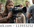 A female cinematographer recording a scene with a professional film camera. Women in film production. 113933252