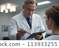 A doctor consults with a patient, clipboard in hand. Professional medical advice in progress. 113933255