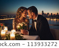 A couple enjoys a romantic dinner with a cityscape backdrop. They share a joyful moment amidst candlelight and skyline views. 113933272