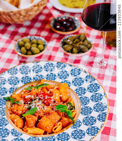 Penne pasta with tomato sauce and glass of red wine 113933648