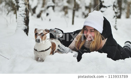 A girl playing with her Jack Russell Terrier dog in the snow. 113933789