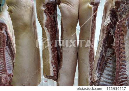 Pork meat in production. Fresh pork carcasses in a meat factory warehouse 113934517