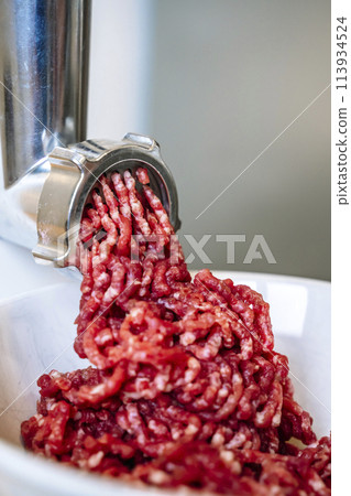 Minced meat and electric meat grinder. Cooking beef minced in the kitchen with an electric grinder 113934524