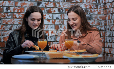 Two cheerful girls in a cafe having dinner. Two cheerful girls in a cafe having dinner. 113934563