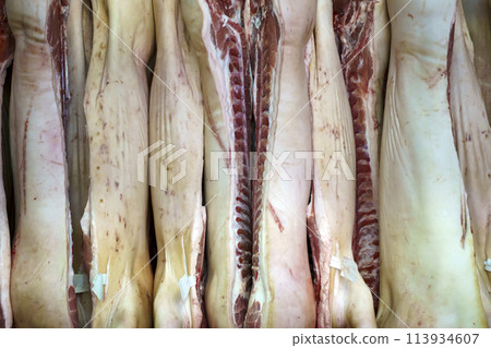 Pork meat in production. Fresh pork carcasses in a meat factory warehouse 113934607