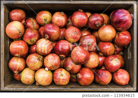 Pomegranate fruit in a box at the market. Farmer's pomegranate harvest Pomegranate fruit in a box at the market. Farmer's pomegranate harvest 113934615