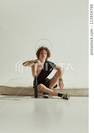 Modern portrait of man dressed as mythology character posing holds baseball bat against white studio background. 113934798