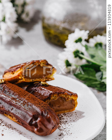 Tasty chocolate eclairs on plate close up Tasty chocolate eclairs on plate close up 113934819