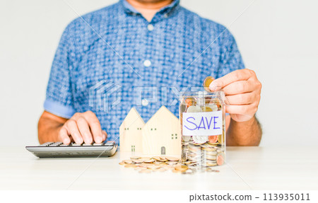 Close-up, Man sits holding and collecting a coin in a jar. Concept of men collects money for a home and car payment during COVID or coronavirus outbreak. Copy space on right. Blurred white background 113935011