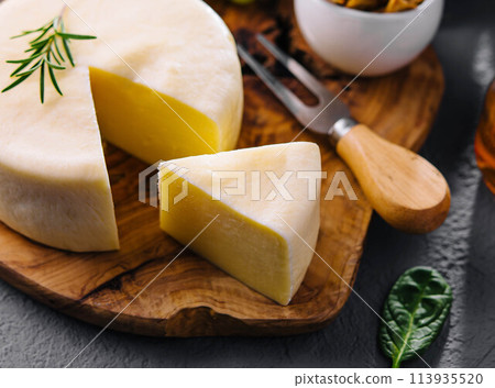 Round cheese on a wooden board close up 113935520