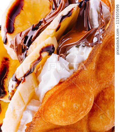 hong kong or bubble waffle with whipped cream, chocolate and bananas close up 113935696