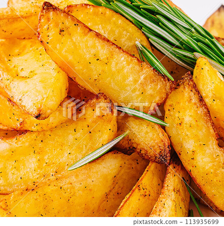 Baked potato wedges with rosemary close up Baked potato wedges with rosemary close up 113935699