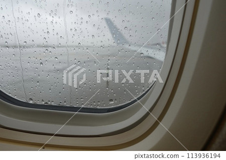 Wing and airport seen from an airplane window with water drops Wing and airport seen from an airplane window with water drops 113936194