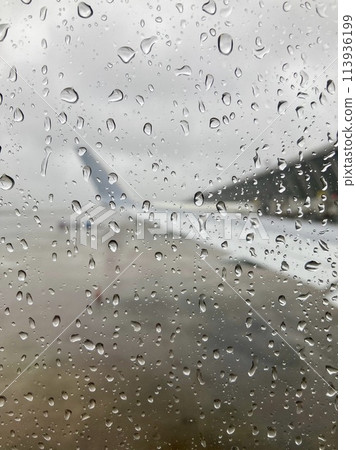 Wing and airport seen from an airplane window with drops Wing and airport seen from an airplane window with drops 113936199