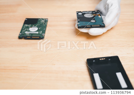 A person is holding a computer hard drive in their hand 113936794