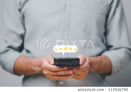 A man is holding a cell phone with a star rating on it A man is holding a cell phone with a star rating on it 113936798