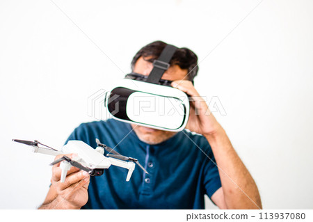 A man is wearing a virtual reality headset and holding a white drone 113937080