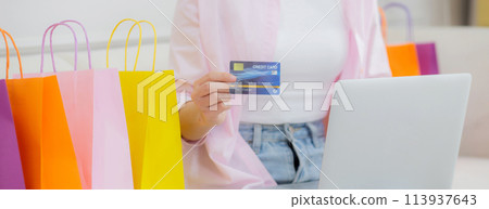 Young asian woman sitting on sofa using laptop computer shopping online with credit card. 113937643